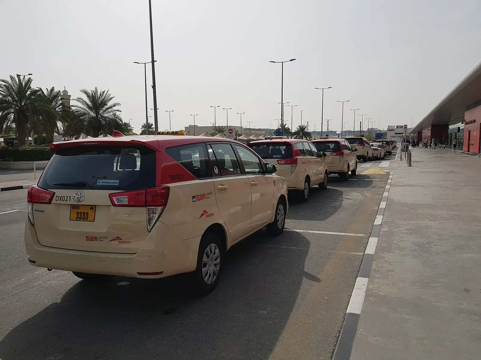 Departures board at Dubai International Airport with a taxi rank outside for layover passengers